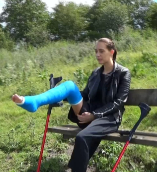 Sunshine angled LLC #62 - With a blue LLC Sunshine is crutching on a walk with wide pants, black leather jacket, a sneakers and red crutches. + other clips!