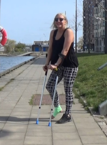 Bella sprain #39 - Bella crutches across a busy road. With her right foot wrapped in a green bandage and with the crutches as support, she tries to hurry across the road before the next car arrives. Bella jumps down towards the harbor...